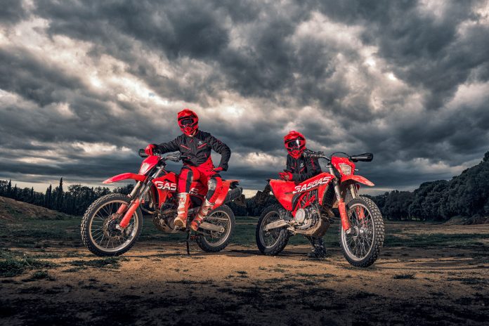 Dos motociclistas con motocicletas rojas GASGAS en la cima de un cerro bajo un cielo nublado en Paraguay