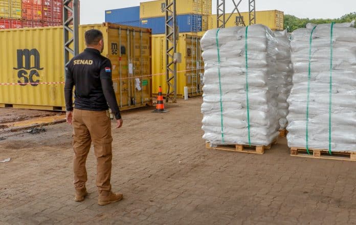 La imagen muestra a un agente de la Senad, de espalda y las bolsas de azucar que contienen cargas de cocaína.